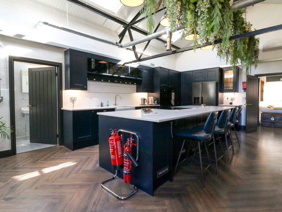 A kitchen with an island and stools at The Old Workshop in Wormshill near Harrietsham