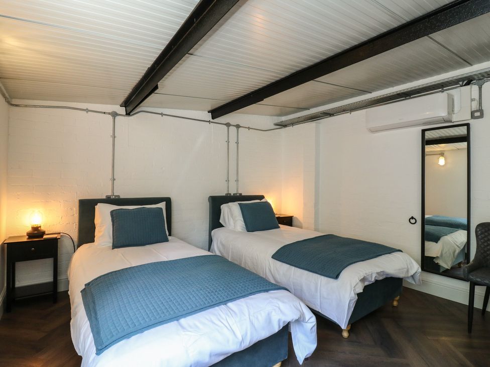 A bedroom with two single beds and a nightstand at The Old Workshop in Wormshill near Harrietsham