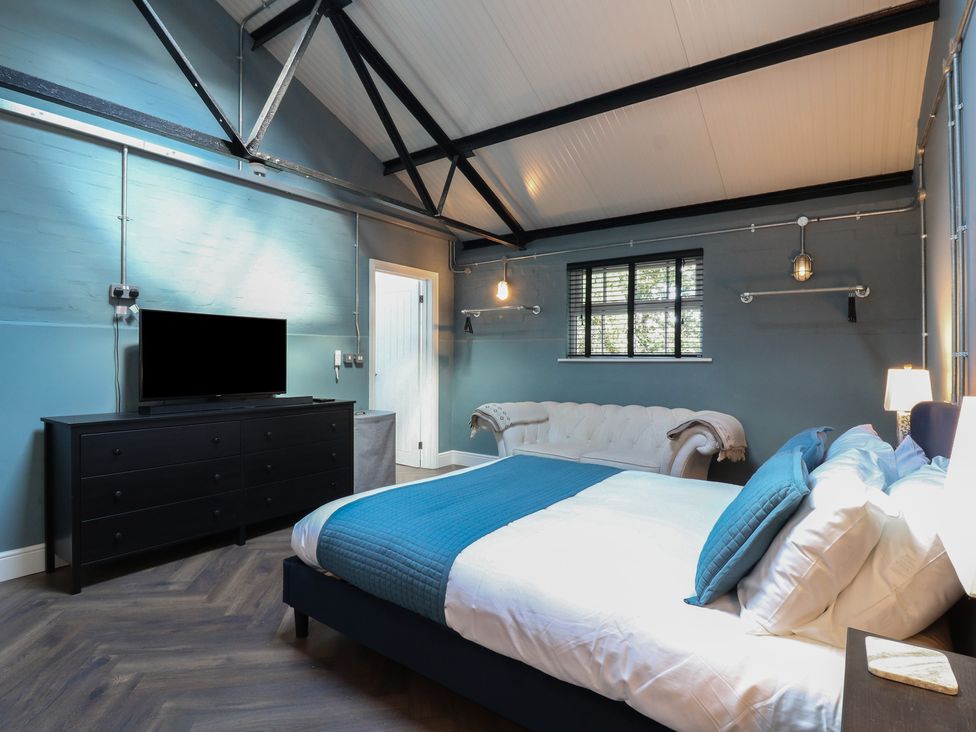 A bedroom with a bed, sofa, and television at The Old Workshop in Wormshill near Harrietsham