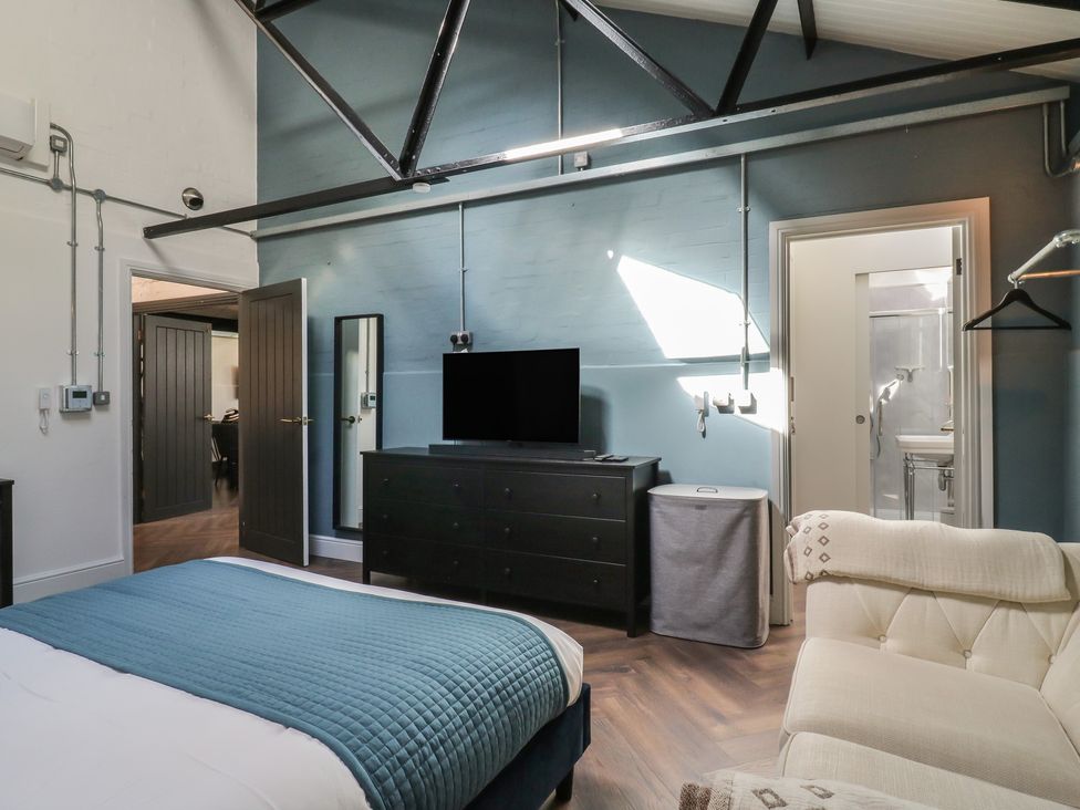 A bedroom with a bed, television, and dresser at The Old Workshop in Wormshill near Harrietsham