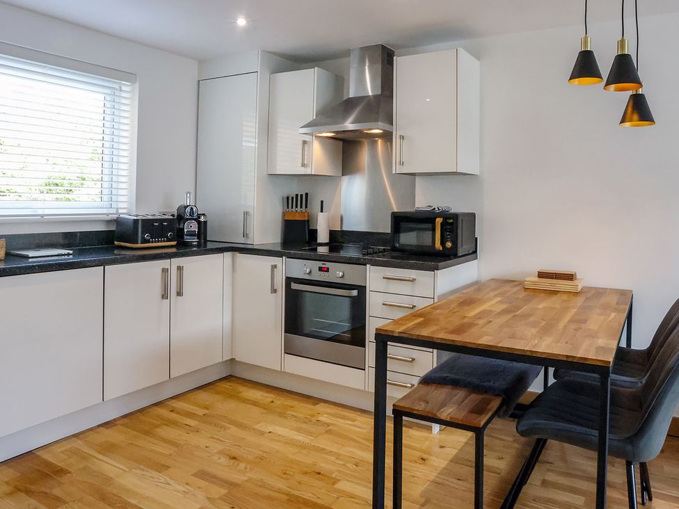 A kitchen with cabinets, stove, and dining table at Whitstable Bay Getaway, Whitstable