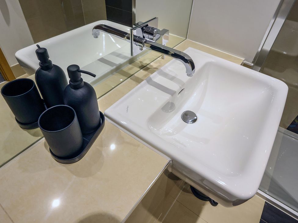 A sink with a tap and black containers on a tray at Whitstable Bay Getaway in Whitstable