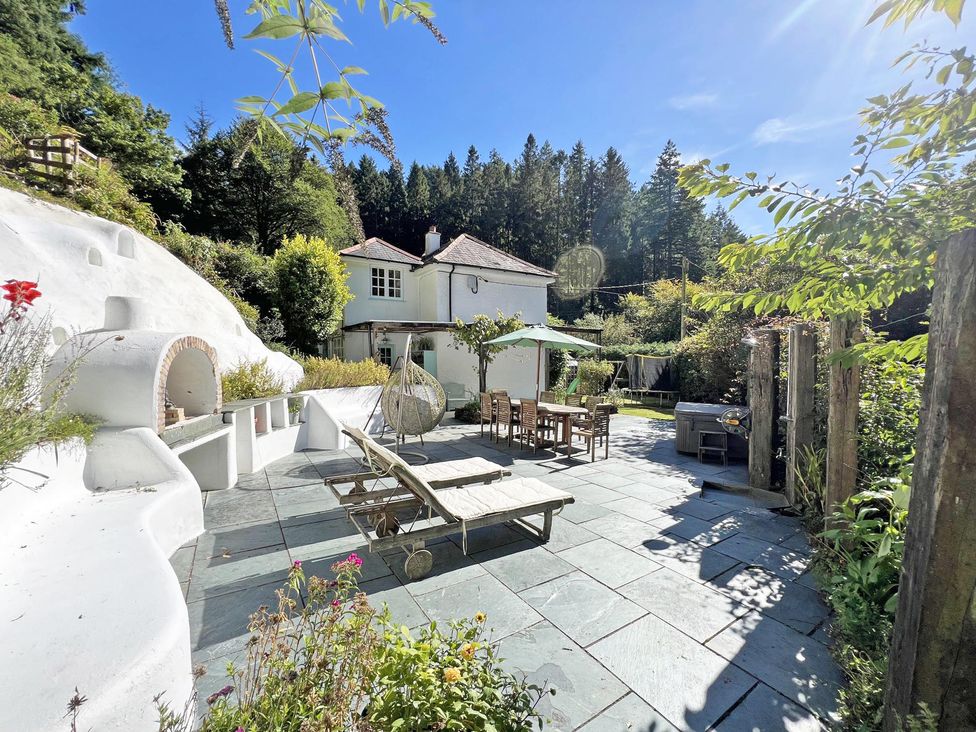 An outdoor patio area with seating and a grill at Lost In The Woods Lodge near Bodmin
