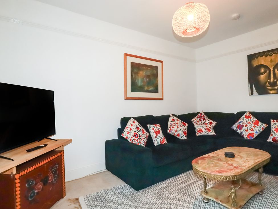 A living room with a sofa and television at Lost In The Woods Lodge near Bodmin