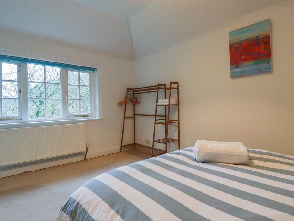 A bedroom with a bed and shelves at Lost In The Woods Lodge near Bodmin