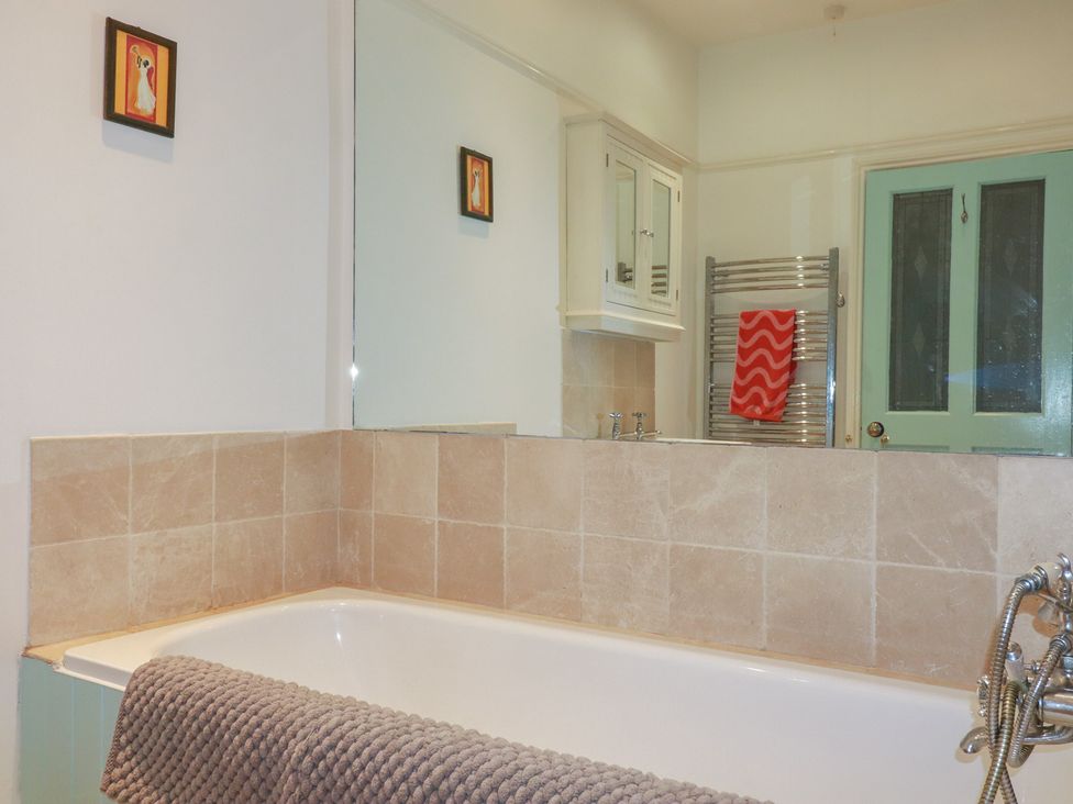 A bathroom with a bath tub and mirror at Lost In The Woods Lodge near Bodmin