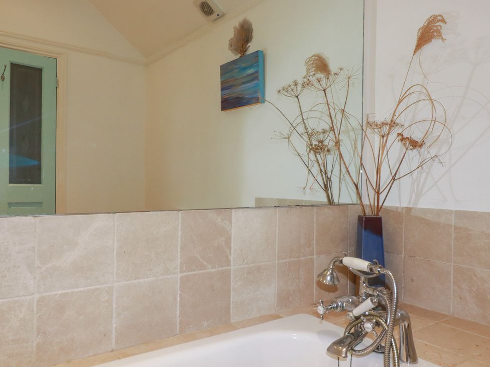 A bathroom with a bathtub and mirror at Lost In The Woods Lodge near Bodmin