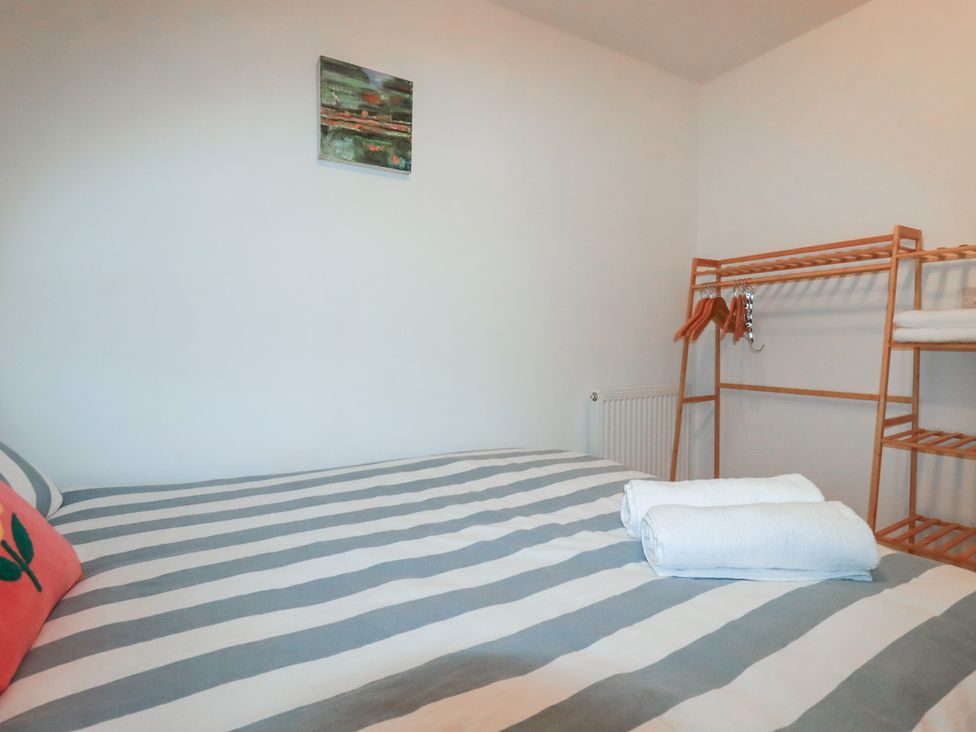 A bedroom with a bed and towels at Lost In The Woods Lodge near Bodmin