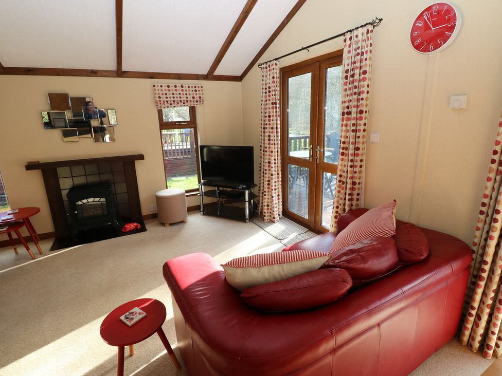 A living room with a sofa and television at Riverside Lodge 3