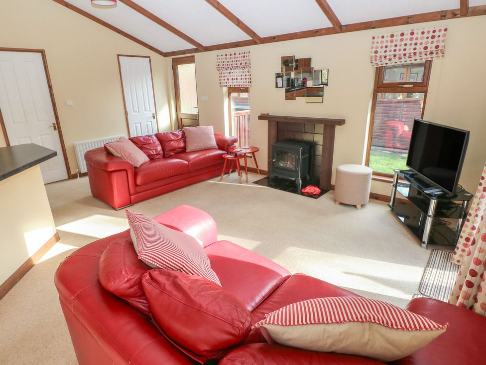 A living room with a sofa and television at Riverside Lodge 3