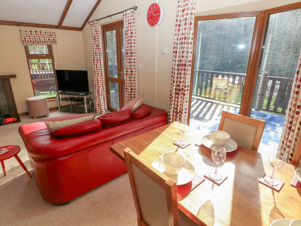 A living room with a television and dining area at Riverside Lodge 3