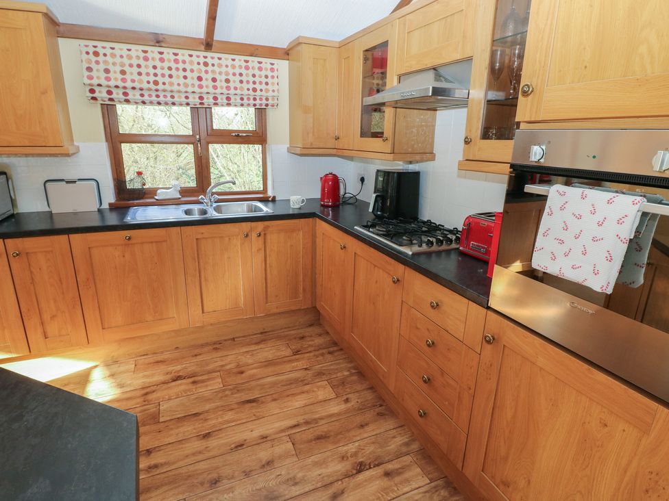 A kitchen with wooden cabinets and appliances at Riverside Lodge 3