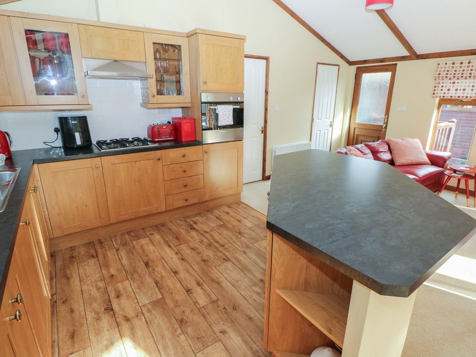 A kitchen with cabinets, stove, and fridge at Riverside Lodge 3