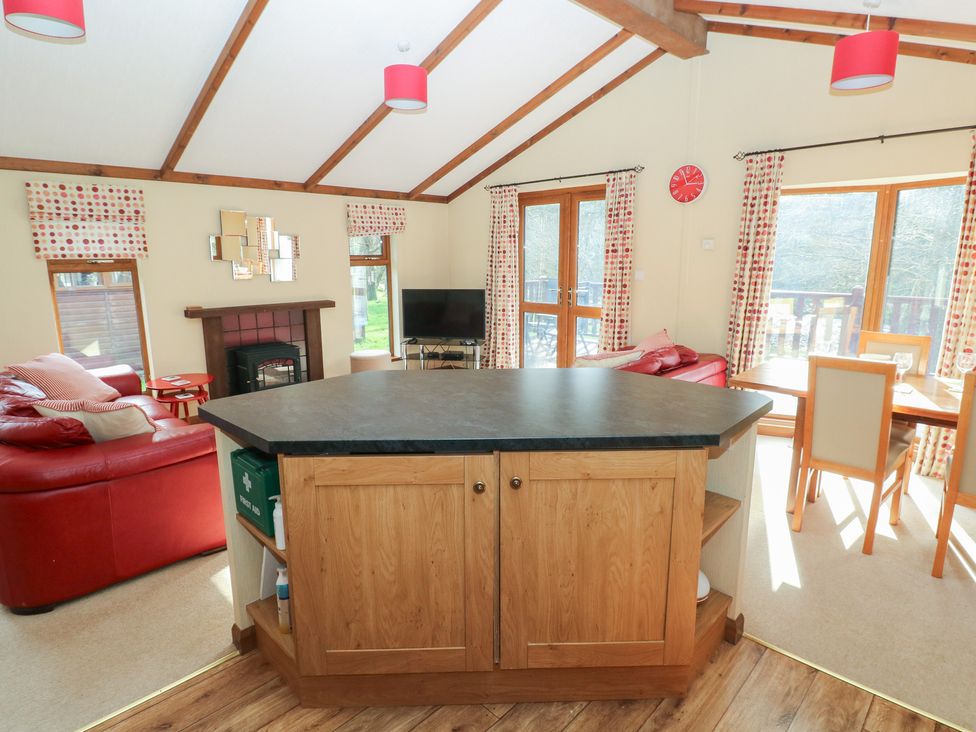A living room with a kitchen island and television at Riverside Lodge 3