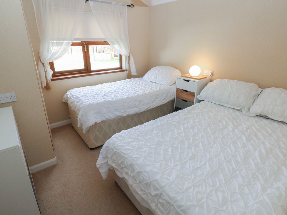 A bedroom with two beds and a bedside table at Riverside Lodge 3