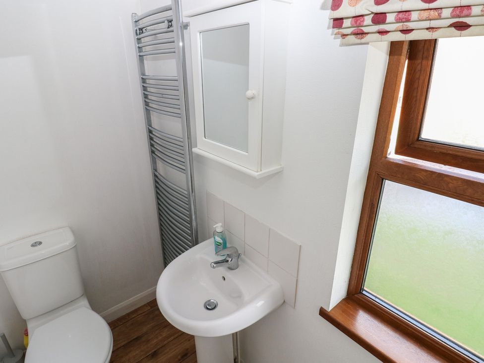 A bathroom with a toilet, sink, towel rail, and window at Riverside Lodge 3 