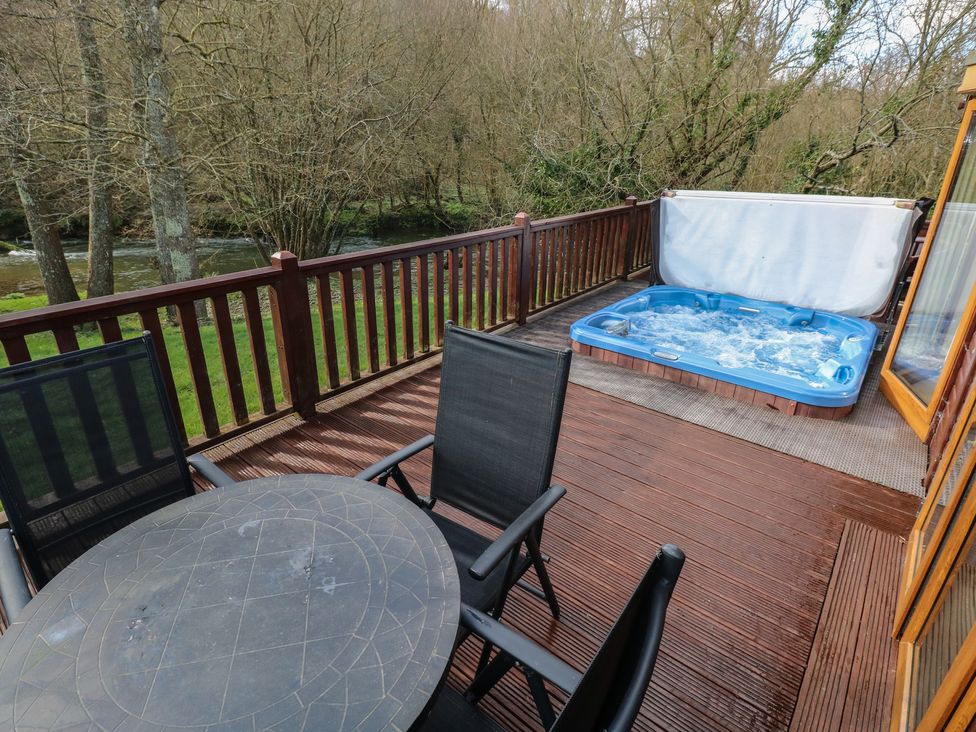 A deck with a hot tub and outdoor furniture at Riverside Lodge 3