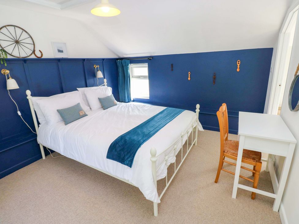A bedroom with a bed and desk at Coach House Cottage