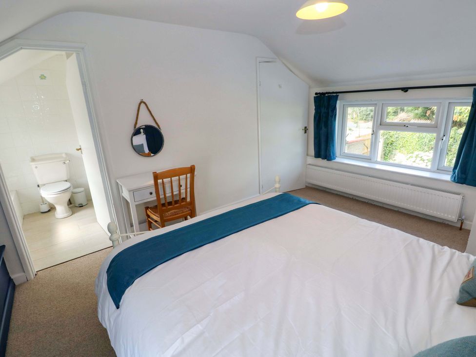 A bedroom with a bed and a window at Coach House Cottage 
