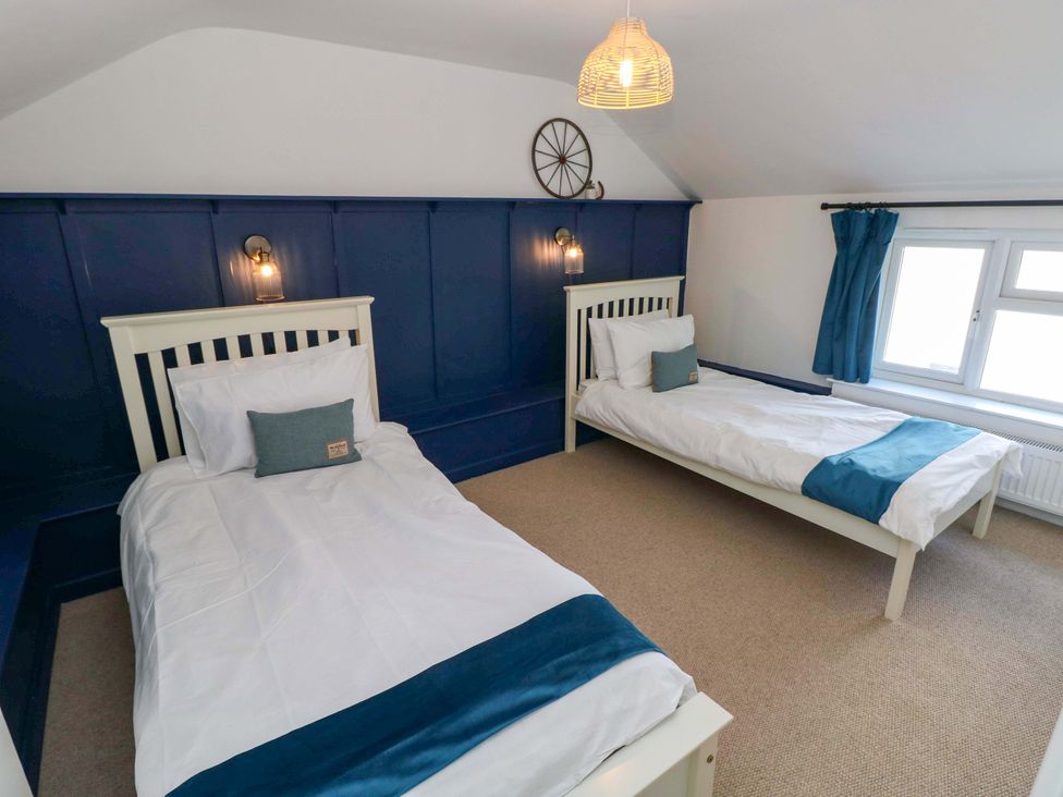 A bedroom with two beds and a window at Coach House Cottage