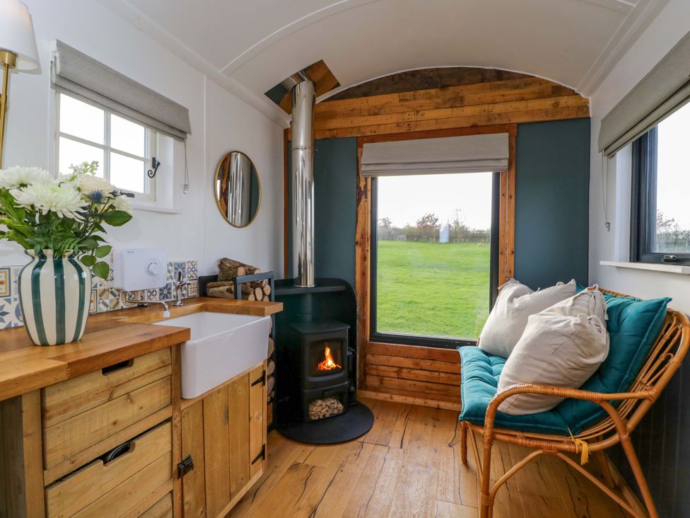 A living room with a fireplace and window at Wiltshire Weavers Hut Sutton Benger near Christian Malford