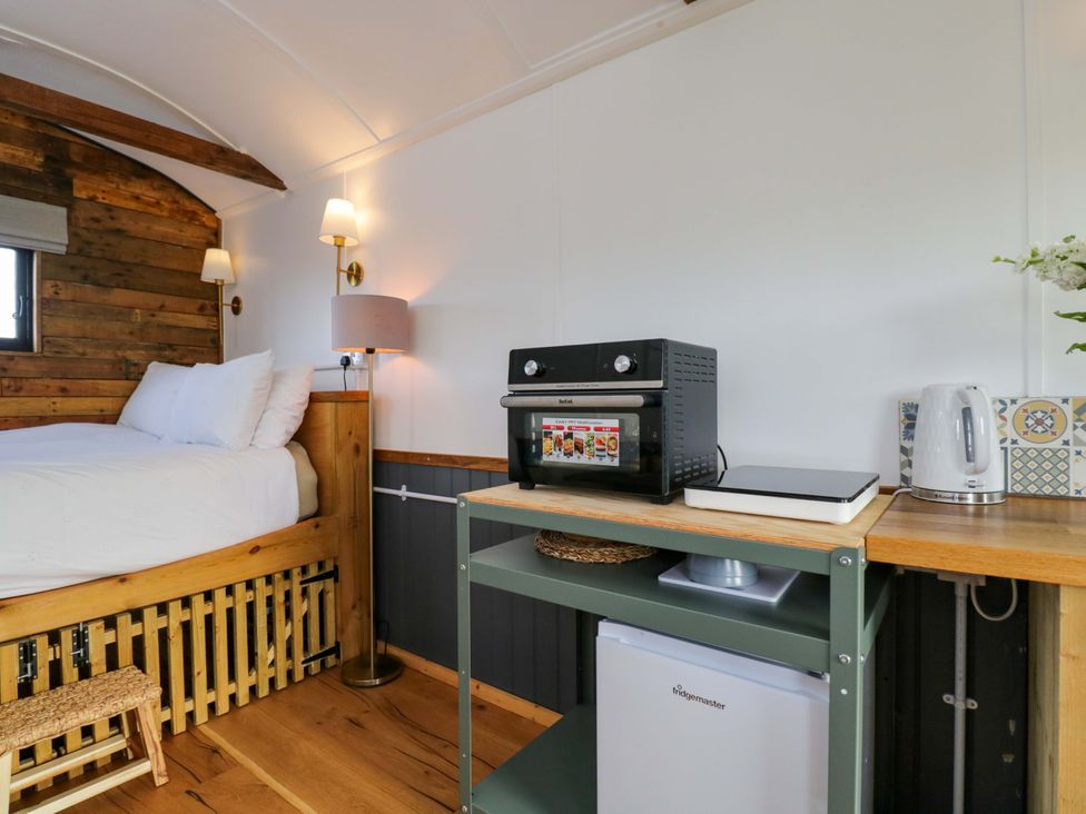 A bedroom with a bed and kitchenette at Wiltshire Weavers Hut Sutton Benger near Christian Malford
