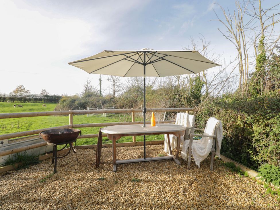 A table with an umbrella and chairs at Wiltshire Weavers Hut Sutton Benger near Christian Malford