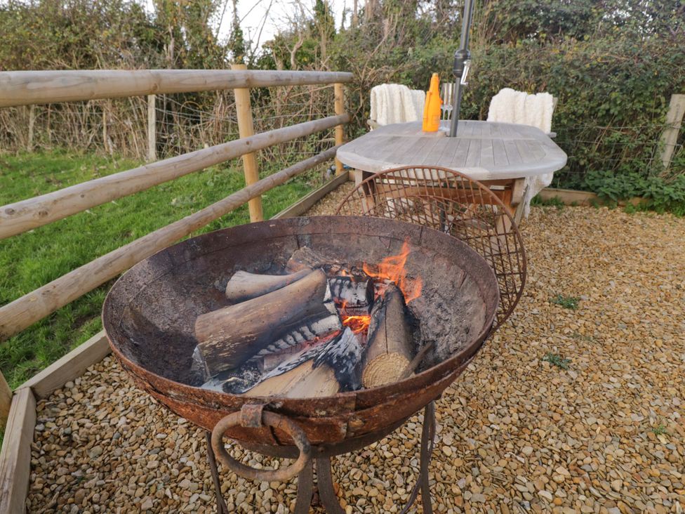 An outdoor area with a fire pit and a table with chairs at Wiltshire Weavers Hut Sutton Benger near Christian Malford