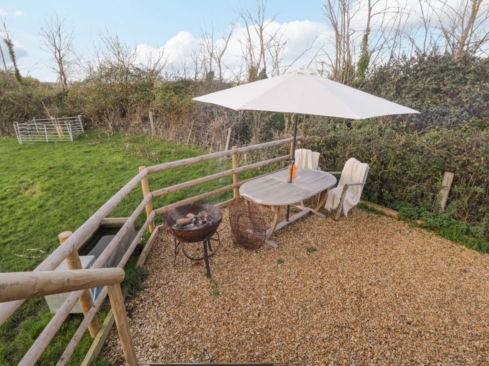 An outdoor space with a table and chairs under an umbrella at Wiltshire Weavers Hut Sutton Benger near Christian Malford
