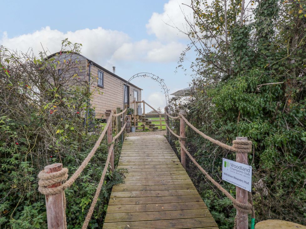 A wooden cabin with a pathway and sign at Wiltshire Weavers Hut Sutton Benger near Christian Malford