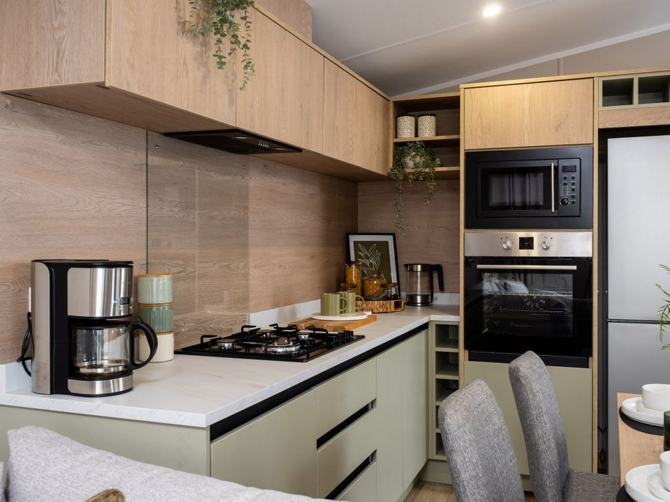 A kitchen with cabinets, gas stove, coffee maker, microwave, and refrigerator at Arlington 40 x 14 Two Bed