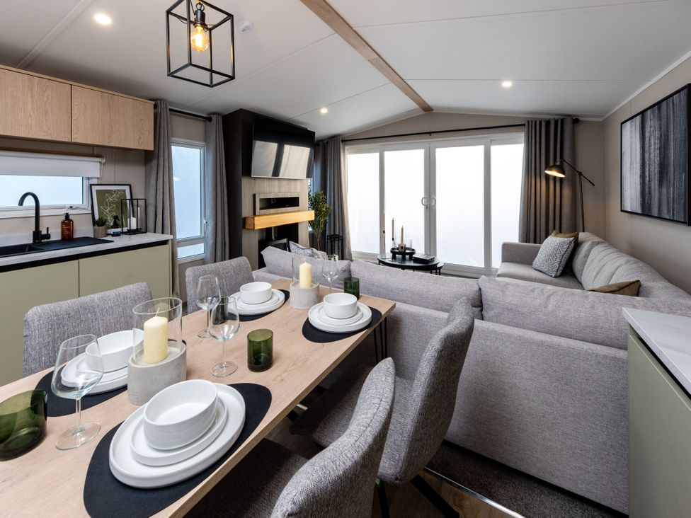 A dining area with a table set for dinner and a sofa at Arlington 40 x 14 Two Bed