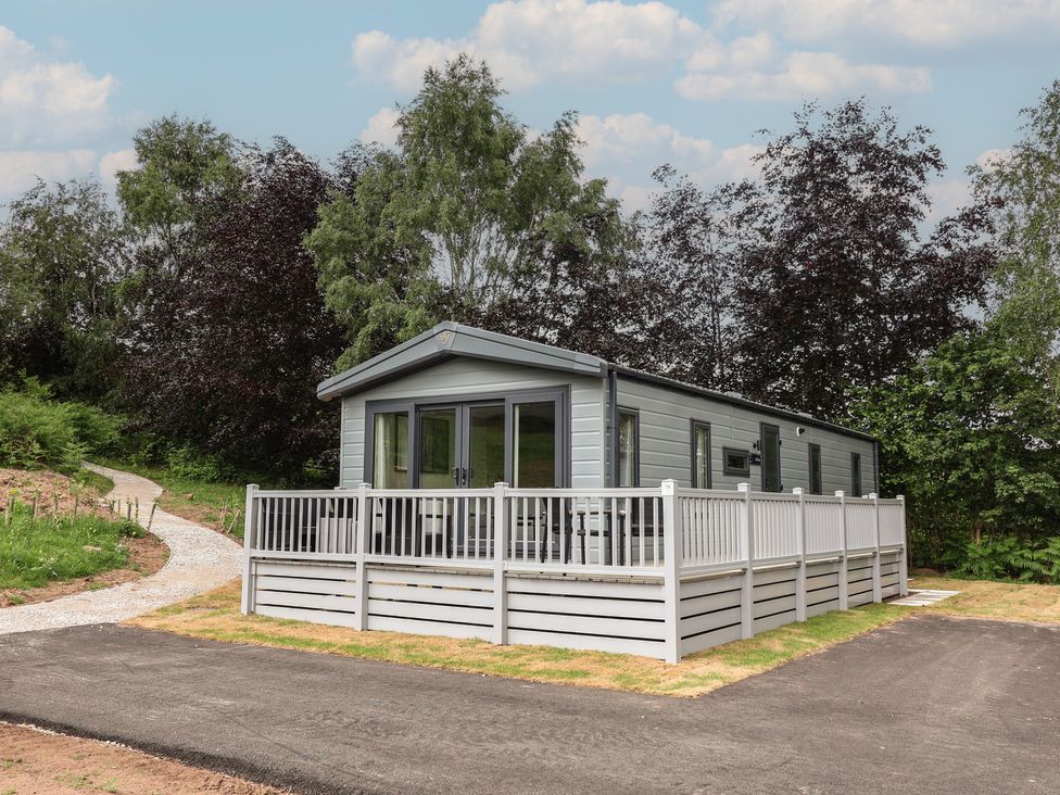A mobile home with a deck and garden area at The Pines 2 Bedrooms in Delamere