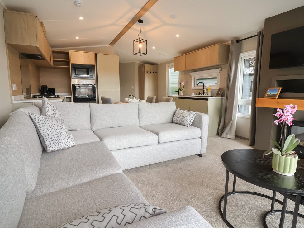 A living room with a sofa and kitchen area at The Pines 2 Bedrooms in Delamere
