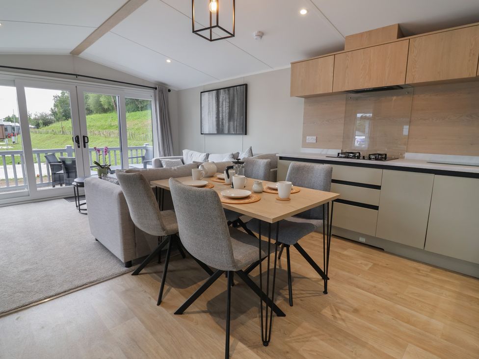 A living room with a dining table and kitchen units at The Pines 2 Bedrooms in Delamere