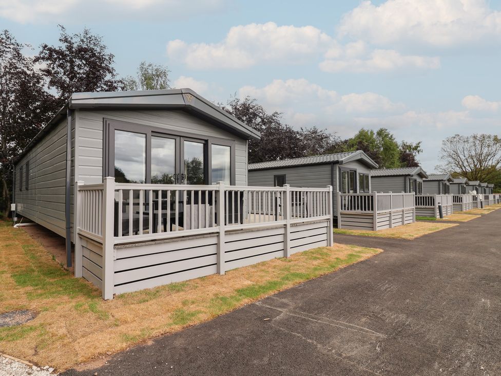 Exterior view of cabins with decks on a pathway at The Pines 2 Bedrooms Delamere