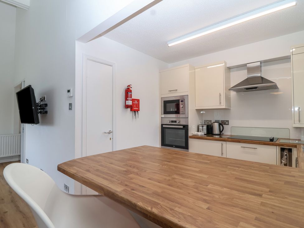 A kitchen with appliances and a wooden table at Harcombe House Bungalow 25 in Chudleigh