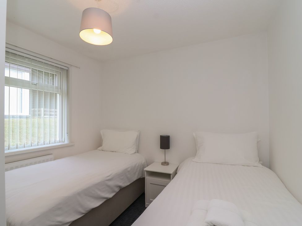 A bedroom with two single beds and a bedside table at Harcombe House Bungalow 25 in Chudleigh