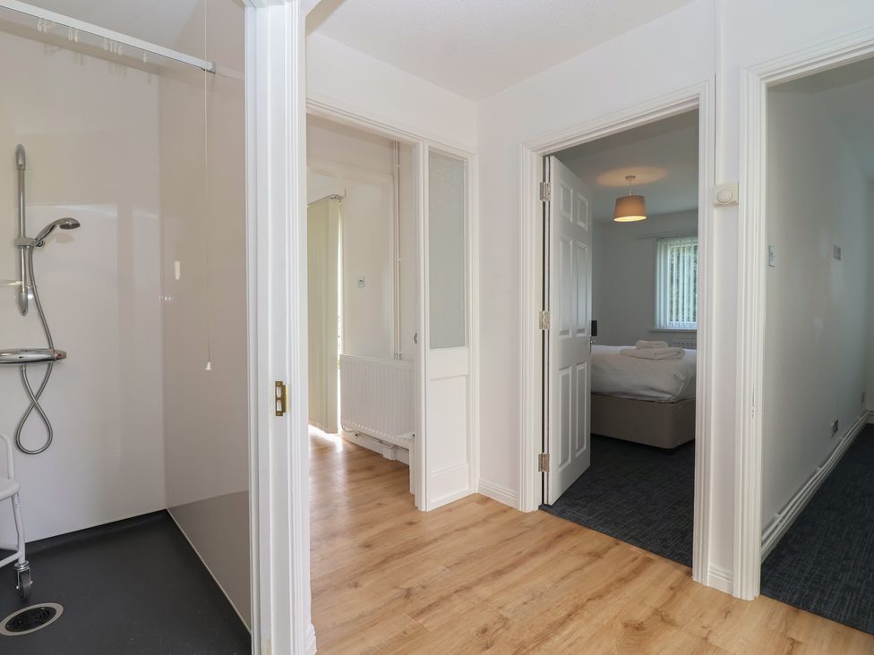 A hallway with a shower and adjacent doors at Harcombe House Bungalow 25 in Chudleigh