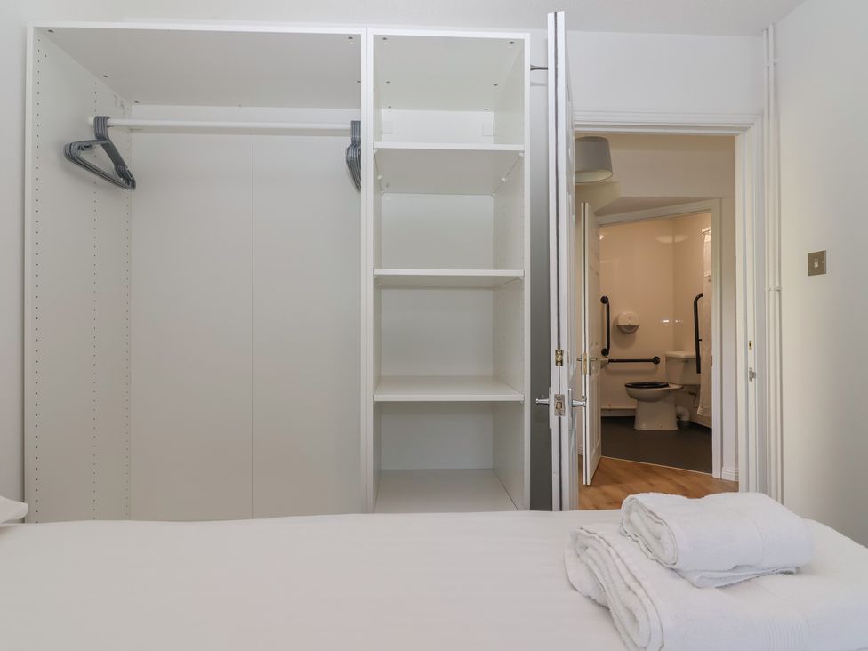 A wardrobe with shelves and a bathroom visible at Harcombe House Bungalow 25 Chudleigh
