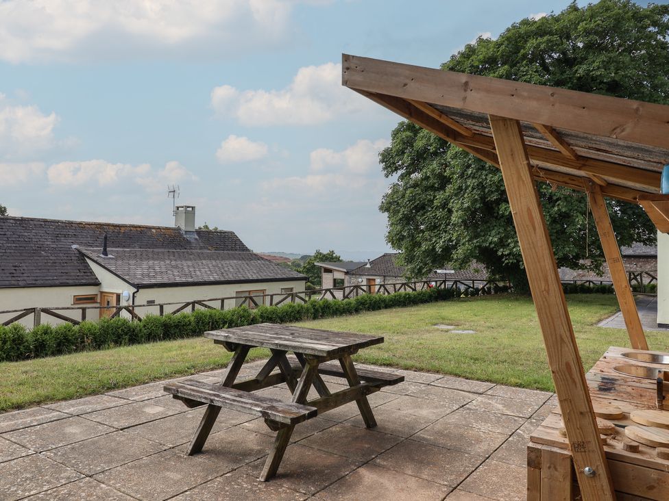 An outdoor area with a table and benches at Harcombe House Bungalow 25 in Chudleigh