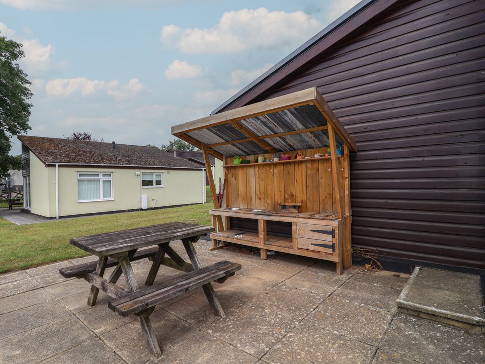 An outdoor area with a picnic table and wooden shelter at Harcombe House Bungalow 25 Chudleigh