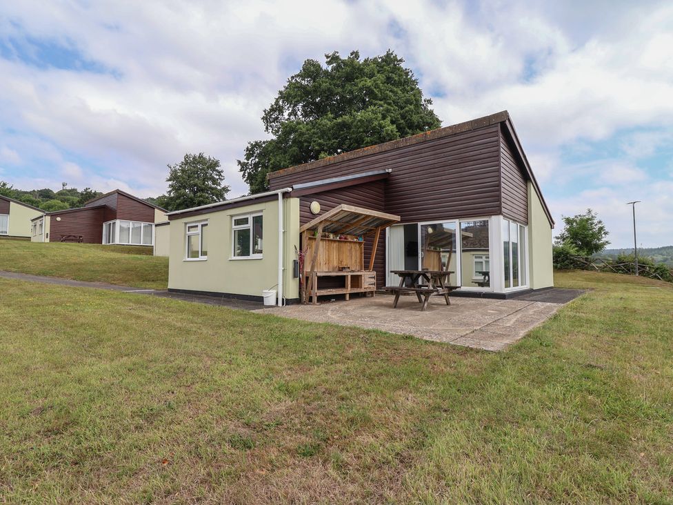 An outdoor area with a bungalow, table and chairs at Harcombe House Bungalow 25 Chudleigh