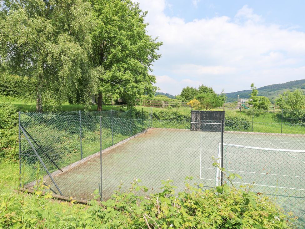 A tennis court surrounded by trees at Harcombe House Bungalow 25 Chudleigh