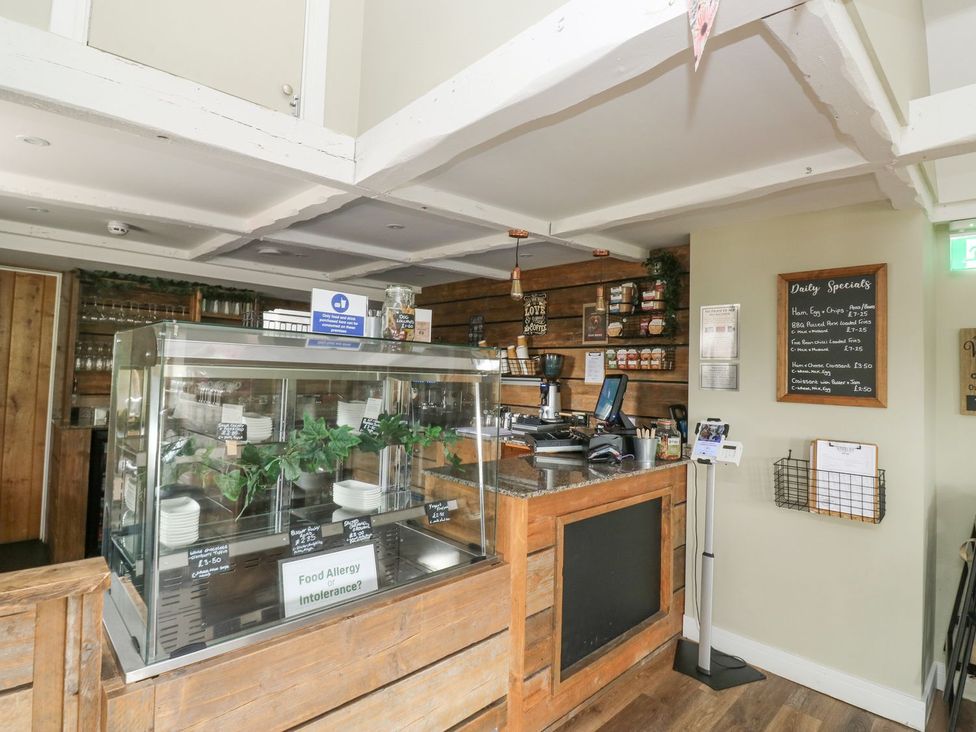 A cafe counter with a display case and menu board at Harcombe House Bungalow 25, Chudleigh