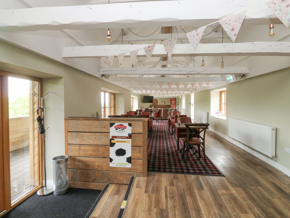 A dining room with wooden furniture and decorative banners at Harcombe House Bungalow 25 Chudleigh