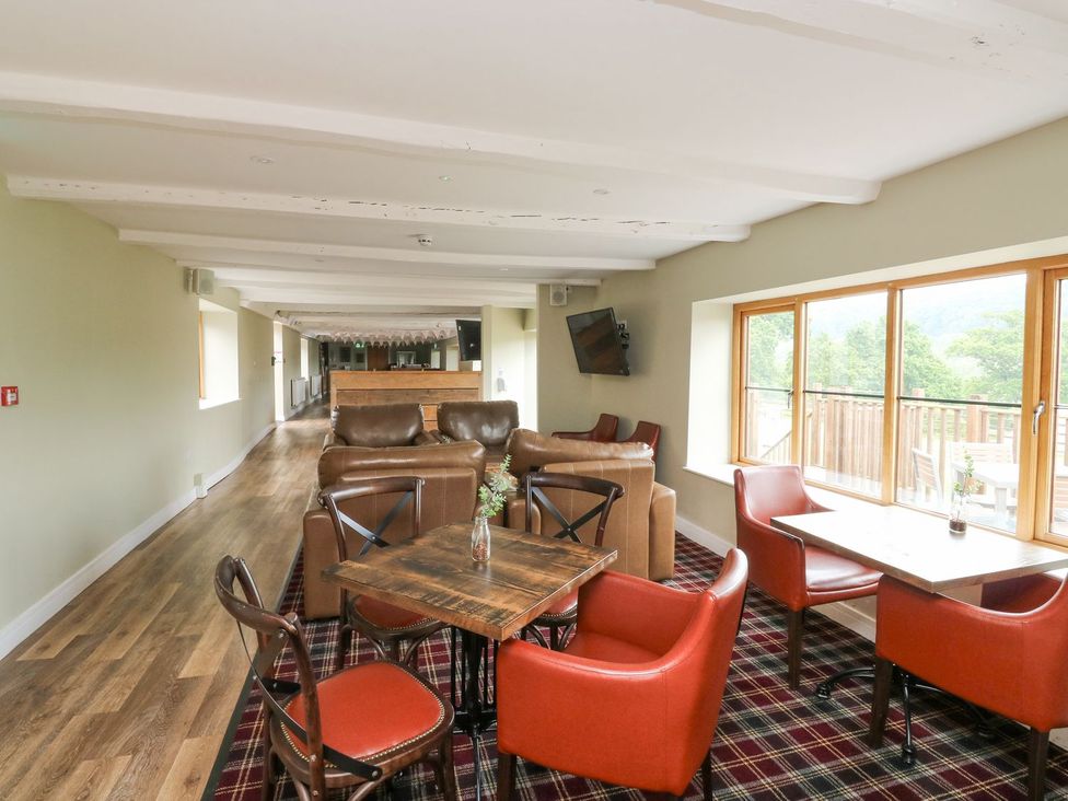 A lounge area with seating and tables at Harcombe House Bungalow 25 in Chudleigh