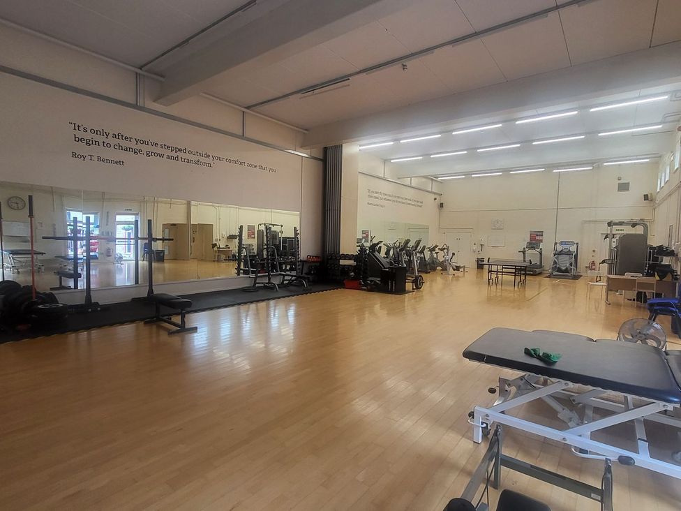 A gym with exercise equipment and mirrors at Harcombe House Bungalow 25 Chudleigh