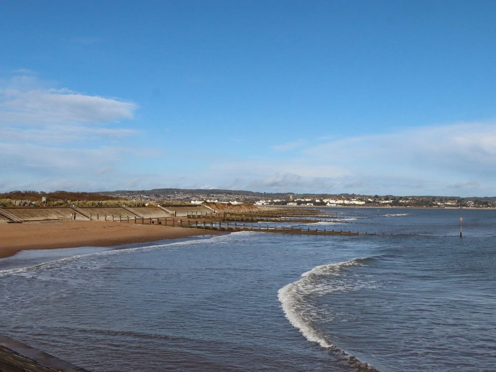 A beach with water and a pier at Harcombe House Bungalow – Pet Friendly with Wet Room Chudleigh