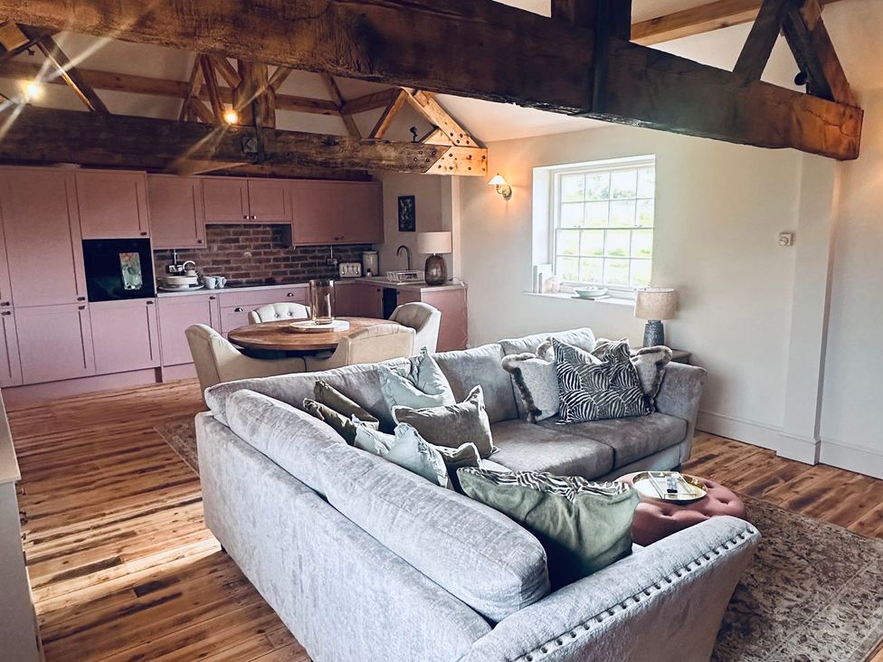 A living room with a sofa and kitchen in Farnah House Barn in Duffield
